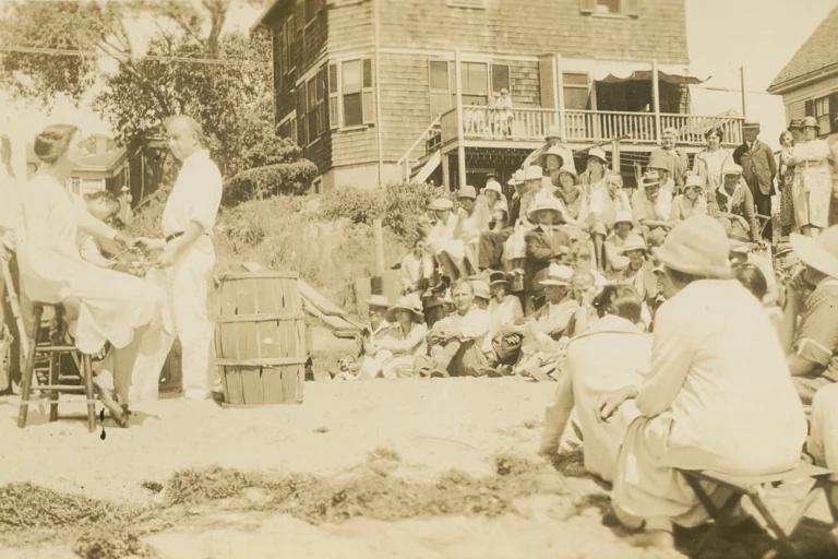 Hawthorne and class 1927 Sepia tone photograph from 1927 of a group of students seated outdoors, observing two people next to a canvas.